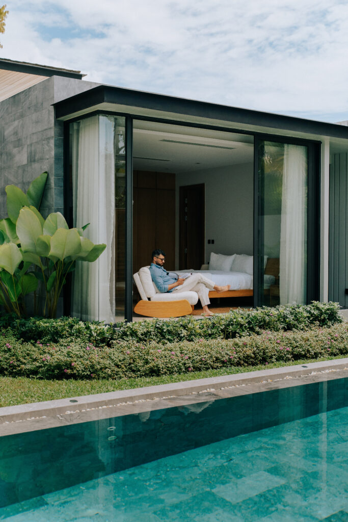 Man reading a book by the pool in soft morning light, illustrating a calm and intimate moment in a luxury villa.