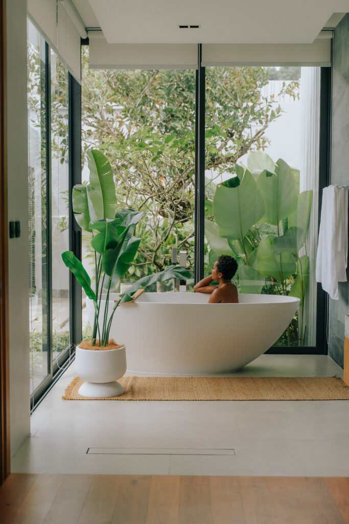 Woman relaxing in a large luxury bathtub with soft lighting, showcasing a serene and elegant villa experience.